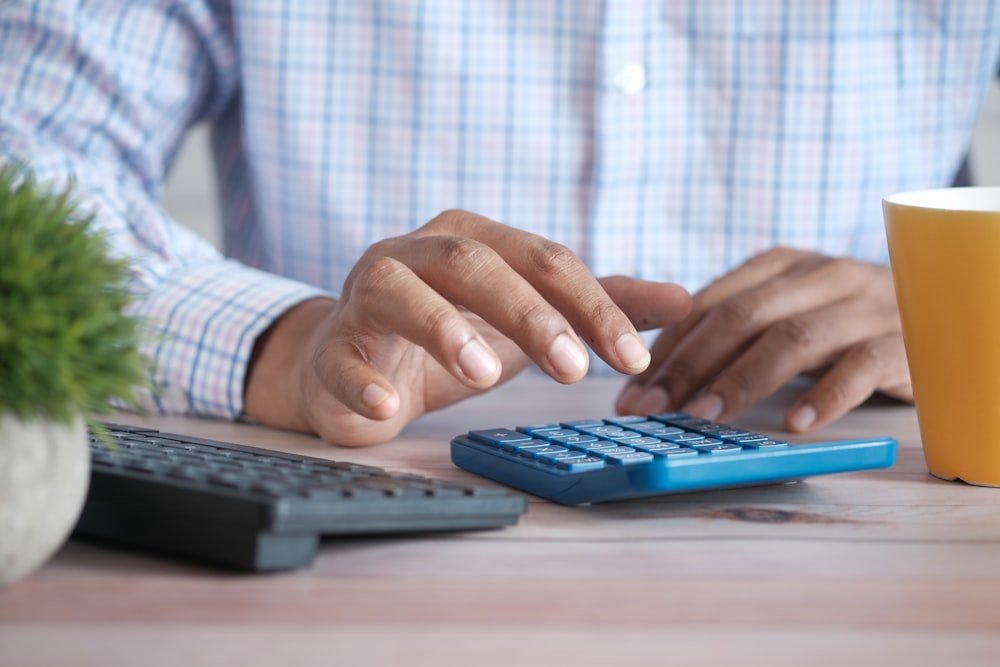 Pessoa usando calculadora para calcular preço de venda e margem de lucro dos produtos